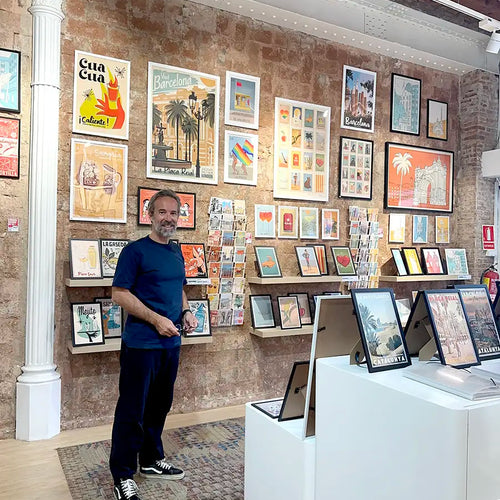 Artist Alecse inside the MyRetroPoster Barcelona gallery surrounded by original limited edition travel posters and decorative art prints from the MyRetroPoster collection.