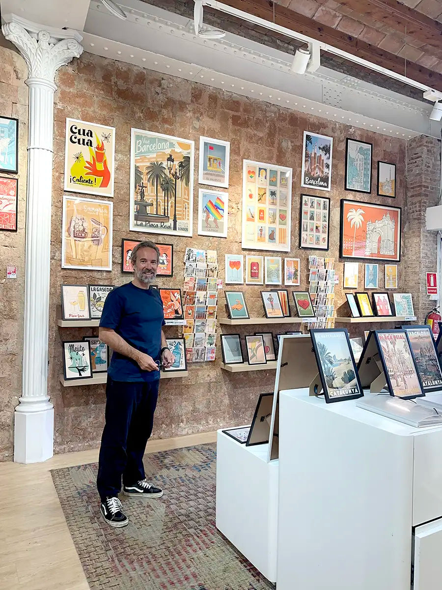 Artist Alecse inside the MyRetroPoster Barcelona gallery surrounded by original limited edition travel posters and decorative art prints from the MyRetroPoster collection.