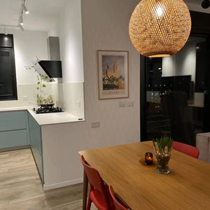 Minimalist dining room with red chairs, warm pendant light and the framed Sitges Sunset poster by Cha hanging on the wall, creating a balanced and elegant interior composition.