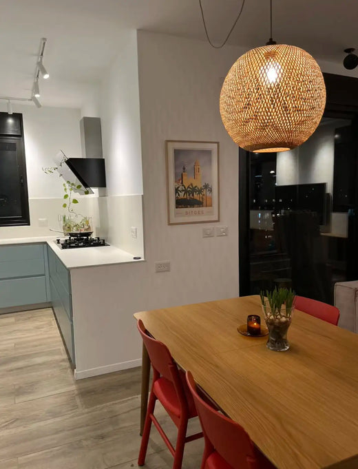 Minimalist dining room with red chairs, warm pendant light and the framed Sitges Sunset poster by Cha hanging on the wall, creating a balanced and elegant interior composition.