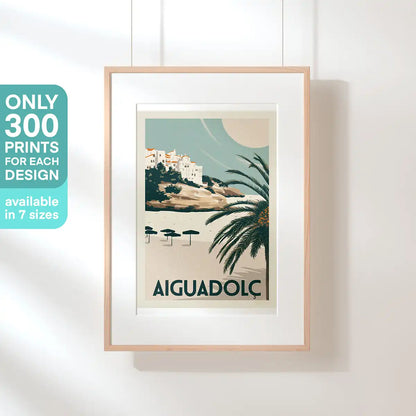 Full view of framed Aiguadolç Spanish Capsule poster by Cha showing beach, palm and Sitges cliffside homes
