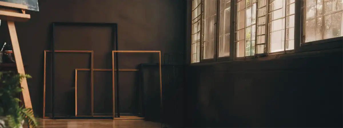 Dark room with large windows allowing natural light to filter in, featuring wooden frames on the floor.