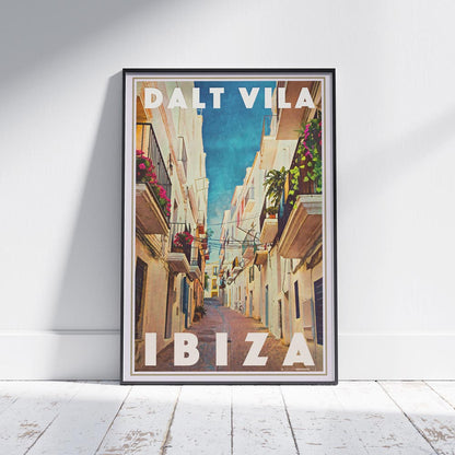 Framed Dalt Vila Ibiza Travel Poster on a white wooden floor, depicting a charming Mediterranean street in Ibiza’s historic old town. Limited edition, 300 copies