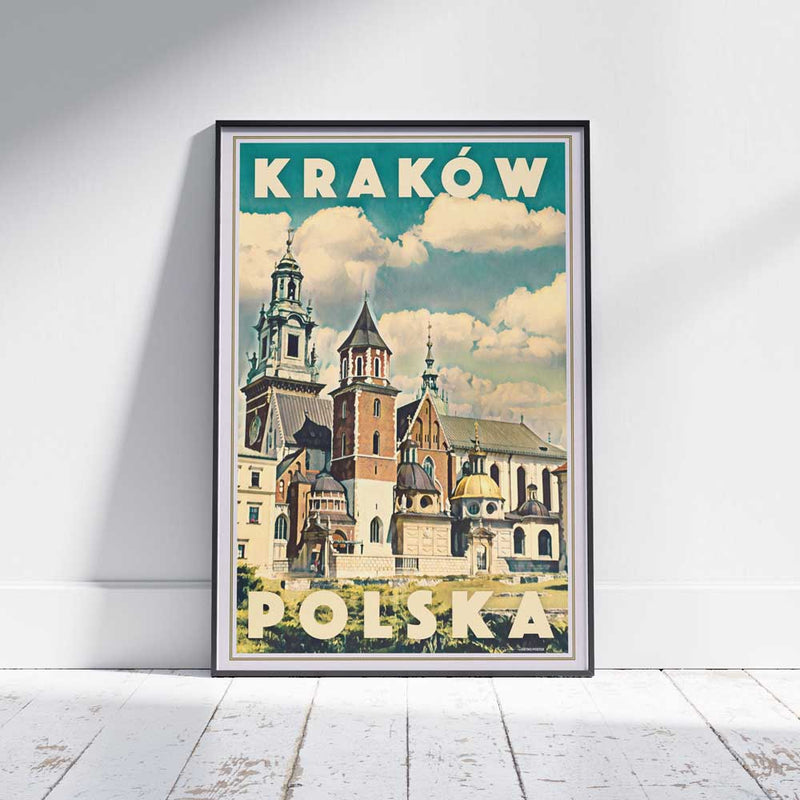 Vintage travel poster of Kraków Poland featuring Wawel Cathedral under a dramatic clouded sky, framed and displayed on wooden floor