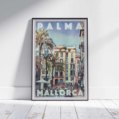 Framed Palma Llotja Travel Poster on a white wooden floor, showcasing a bustling square with palm trees and colorful buildings. Limited edition, 300 copies