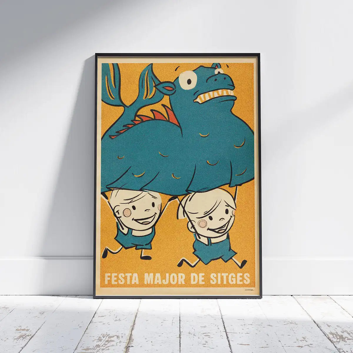 Framed Festa Major Sitges poster by Cha on white wooden floor, featuring children carrying a big blue dragon
