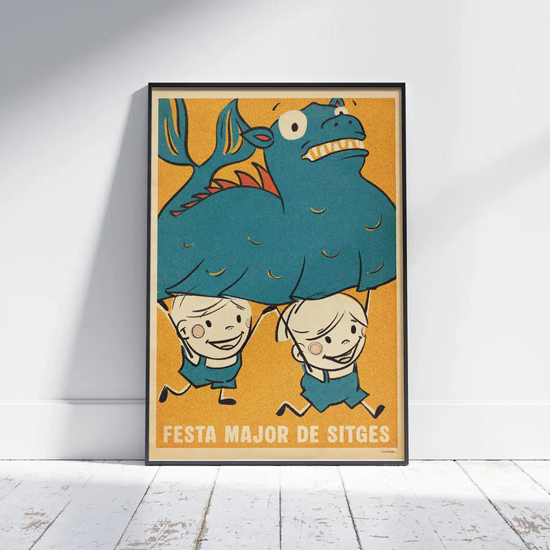 Framed Festa Major Sitges poster by Cha on white wooden floor, featuring children carrying a big blue dragon