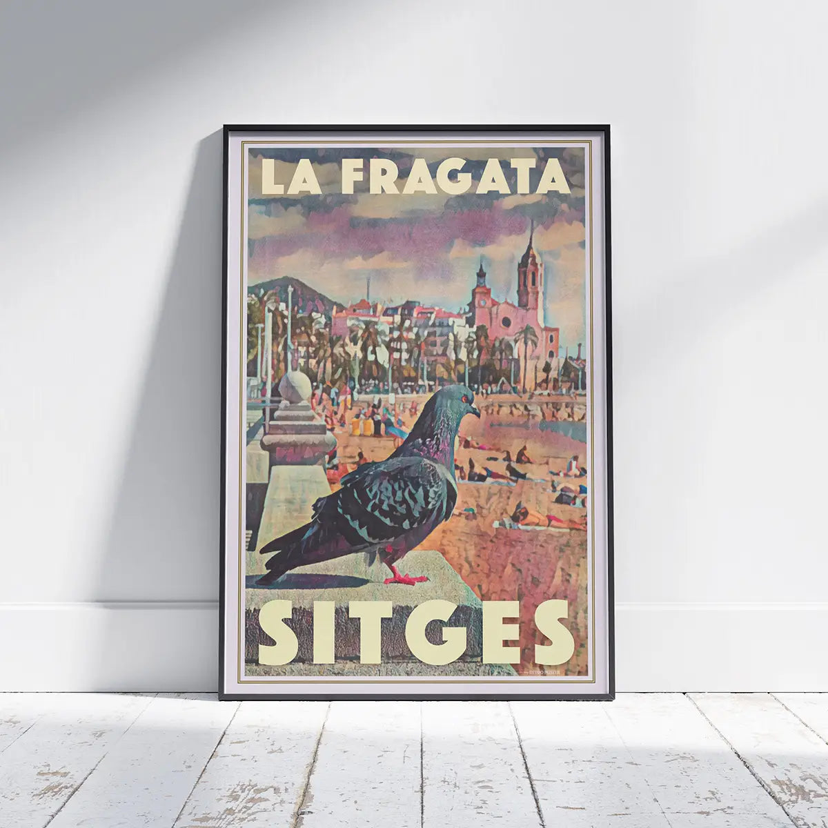Framed Sitges Pigeon La Fragata travel poster displayed on a wall with the church of Sant Bartomeu i Santa Tecla in the background
