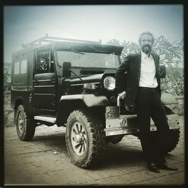 Poster artist Alecse, a retro enthusiast, posing in front of his vintage Jeep at Galle Fort, Sri Lanka, showcasing his passion for classic style and travel