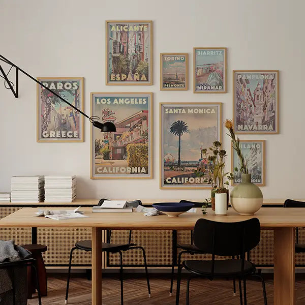 Vintage travel poster gallery wall with retro illustrations by Alecse, featuring destinations like Paris, Tokyo, Barcelona, Santa Monica, and Naples in warm tones, styled in a cozy living room.