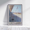 Travel poster of Deauville Boardwalk in a frame on a white wooden floor